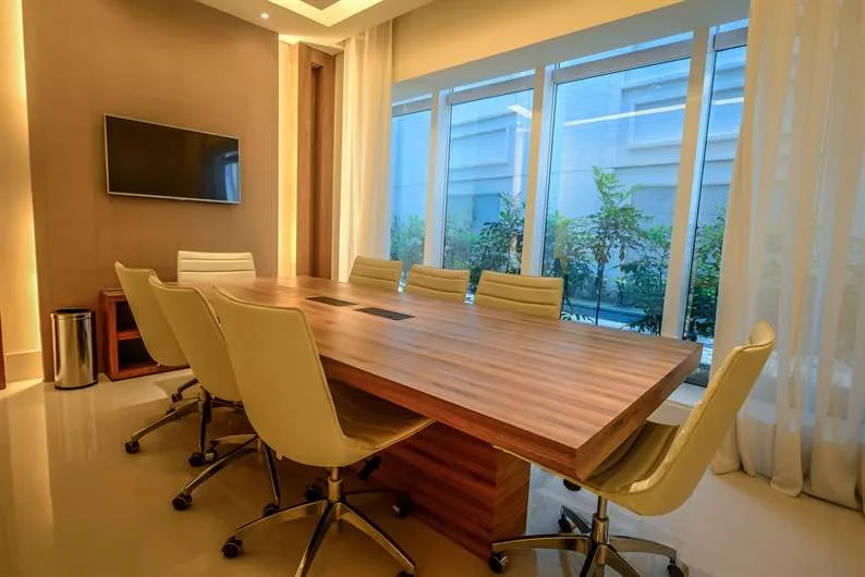 Sala de reunião com mesa de madeira e janelas amplas